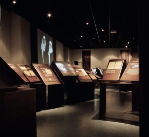 Photo of Mazamet Cathar museum room. Dark room displaying a few booths and photos.